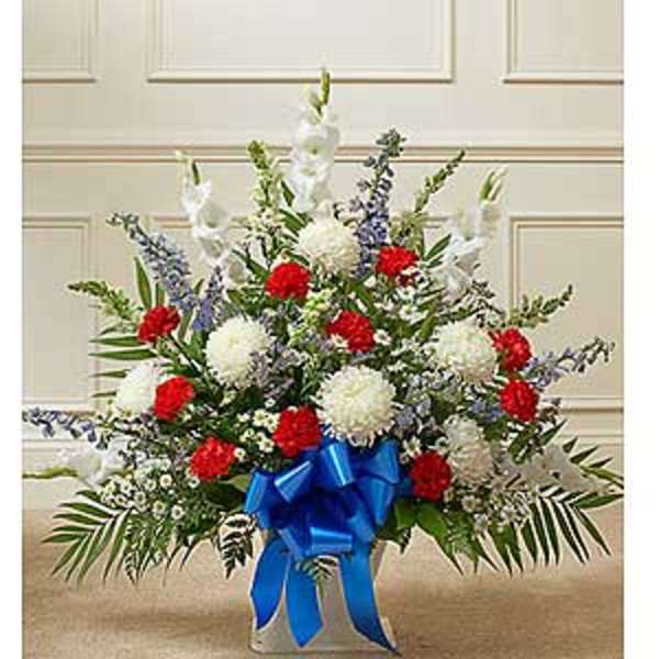 Red and white floral spray with a blue ribbon in a vase