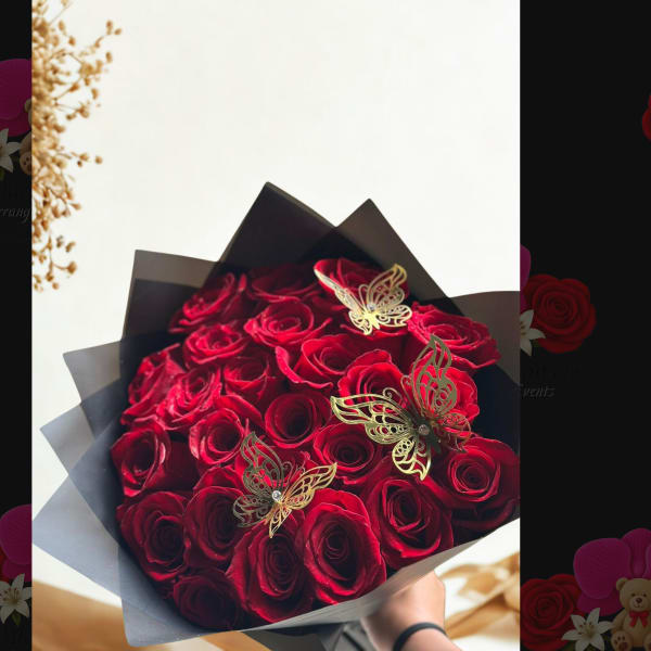 Bouquet of red roses wrapped in black paper with gold butterfly accents