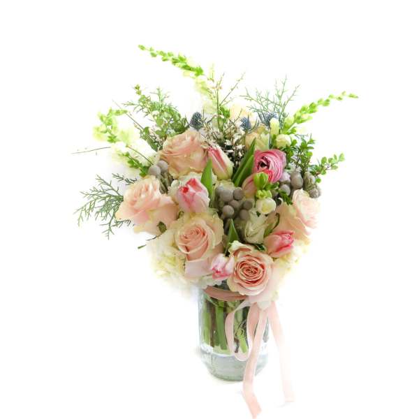 Pink and cream rose bouquet in a glass vase with a ribbon