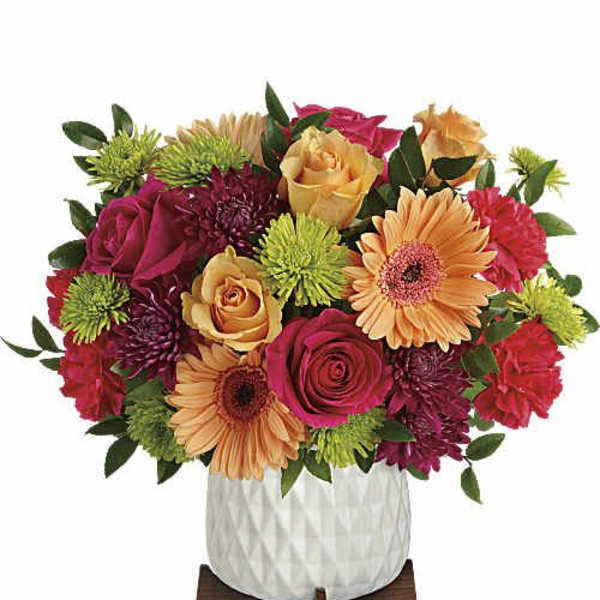 Colorful mixed bouquet in a white vase on a wooden stand