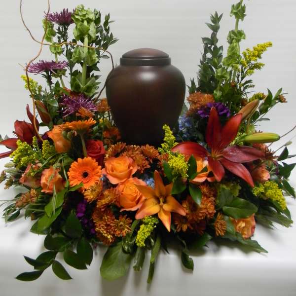 Orange and purple floral arrangement around a dark urn