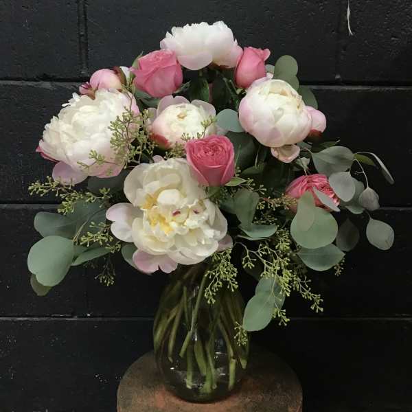 Pink and white peonies and roses in a glass vase