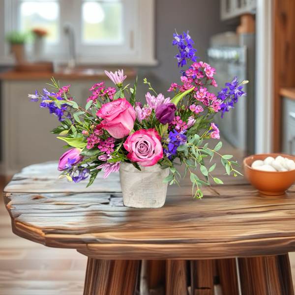 Pink and purple mixed bouquet in a white vase on a wooden table