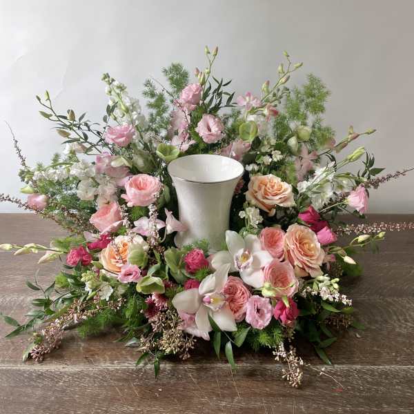 Pink and white floral wreath around a white vase centerpiece