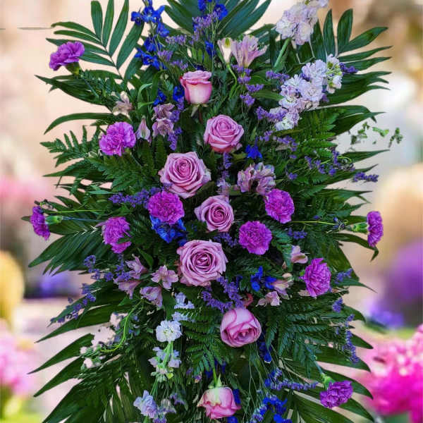 Tall standing floral spray with pink roses and purple blooms on a metal easel