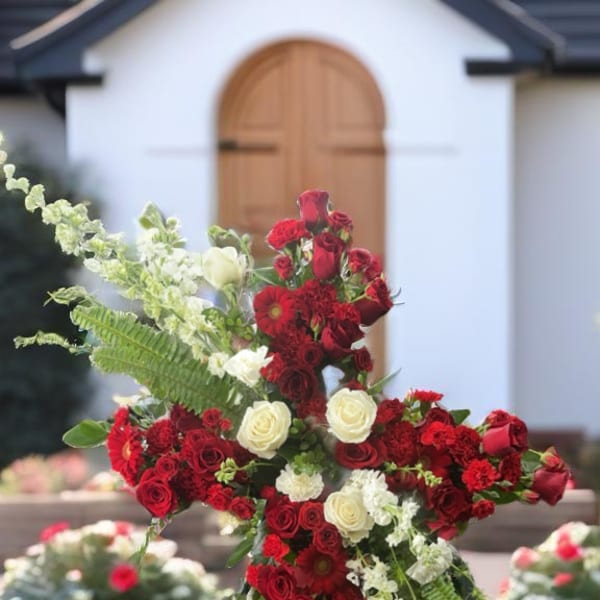 Cross-shaped floral tribute of red and white roses on an easel