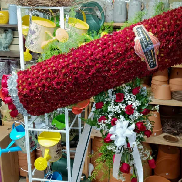 Large red floral spray with roses and white ribbon on a stand