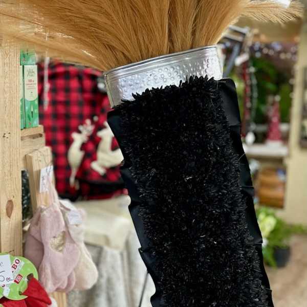 Black memorial spray with tan dried grass in a silver vase