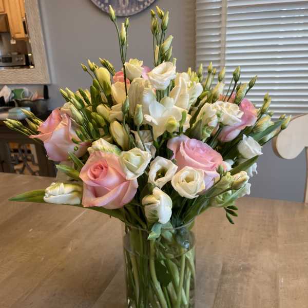 Pink and white flowers arranged in a clear glass vase