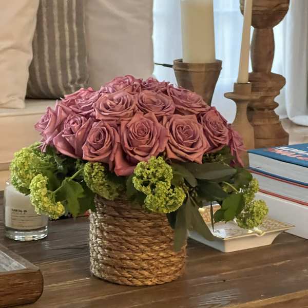 Pink rose arrangement in a woven basket with green blooms