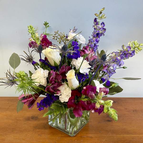 Mixed bouquet in a square glass vase with white, purple, and pink flowers