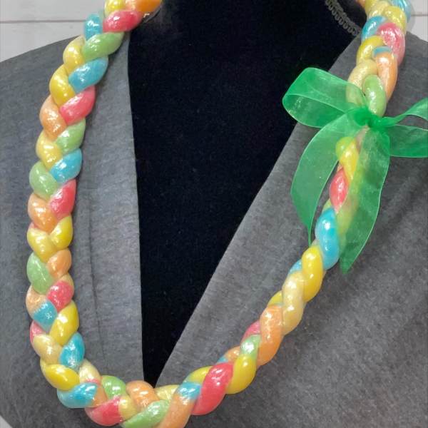 Braided multi-color candy lei with green ribbon bow displayed on a black mannequin