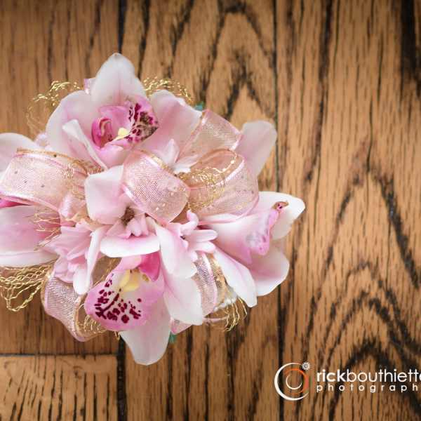 Pink orchid corsage with ribbon on a wooden surface