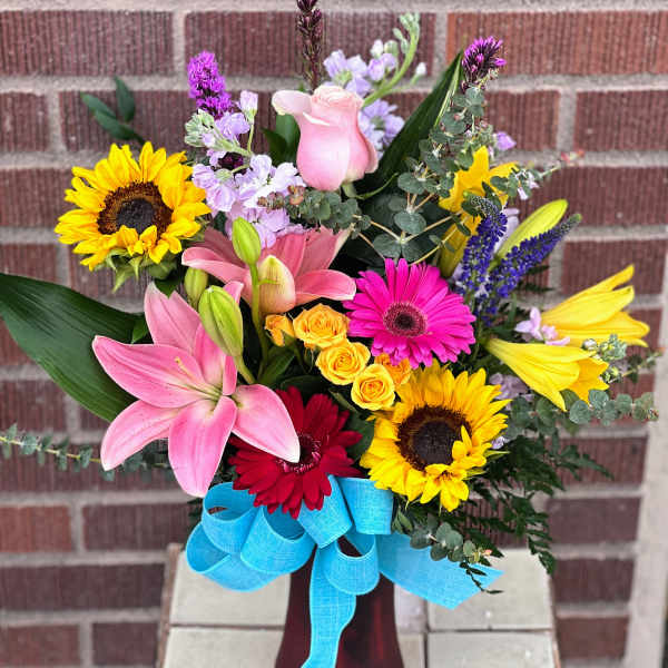 Colorful mixed bouquet with lilies, sunflowers, roses, and gerbera daisies in a vase