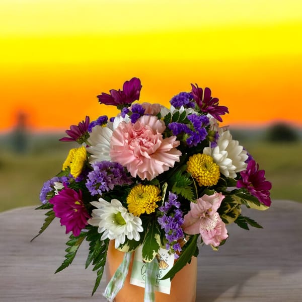 Mixed bouquet of pink, white, yellow, and purple flowers in a glass vase