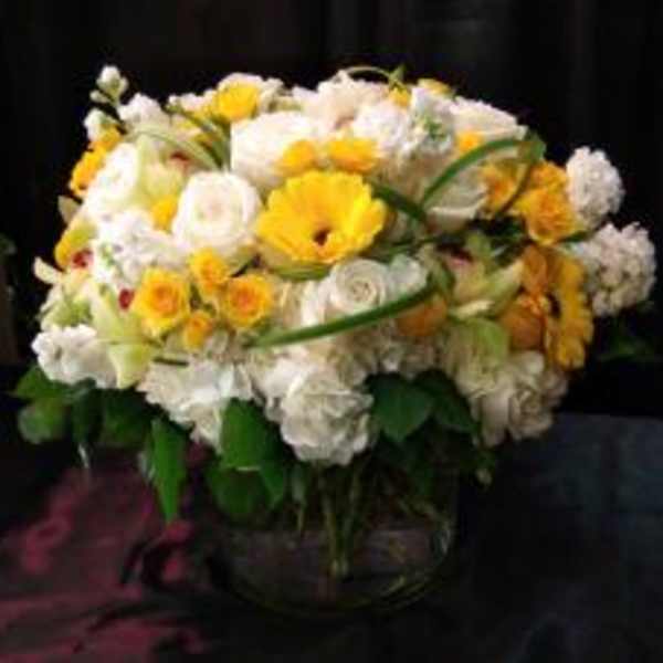 Yellow and white mixed flower arrangement in a glass vase