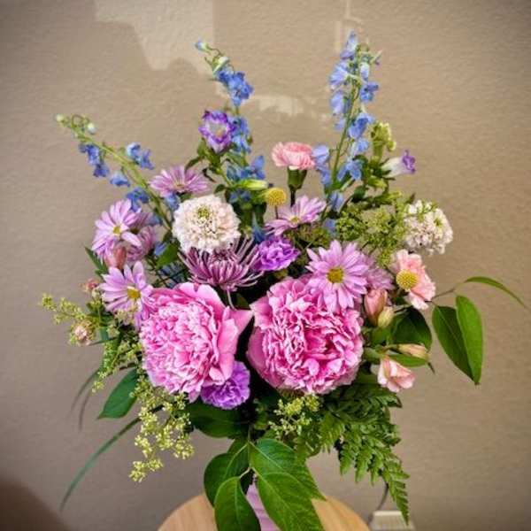 Pink peonies and purple-blue mixed flowers in a pink vase