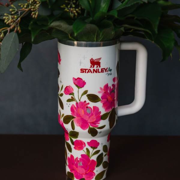 Floral-decorated Stanley tumbler holding greenery and pink flowers