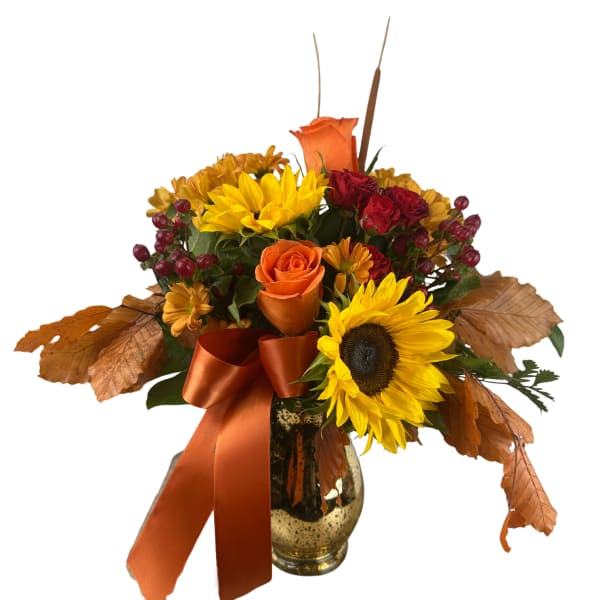 Autumn bouquet with sunflowers, roses, and a ribbon in a glass vase