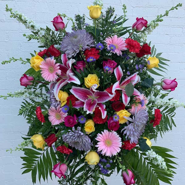 Large standing floral spray with pink, yellow, red, and lavender flowers