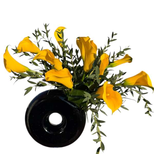 Yellow calla lilies in a black vase with trailing greenery