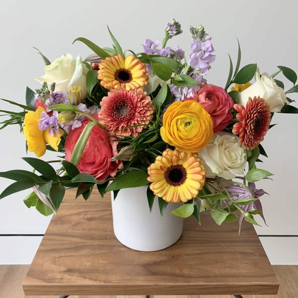 Mixed bouquet in a white vase with yellow, pink, white, and lavender flowers