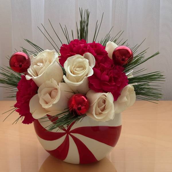 White roses and red carnations in a red-and-white vase with red ornaments
