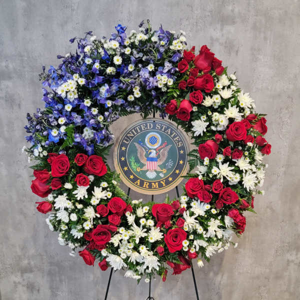 Large floral wreath with red roses, white daisies, and blue flowers around a U.S. Army emblem