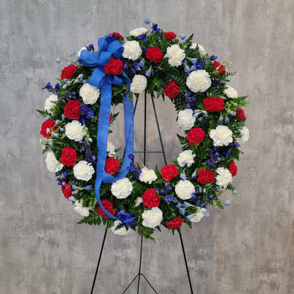 Circular floral wreath with red, white, and blue flowers on a stand