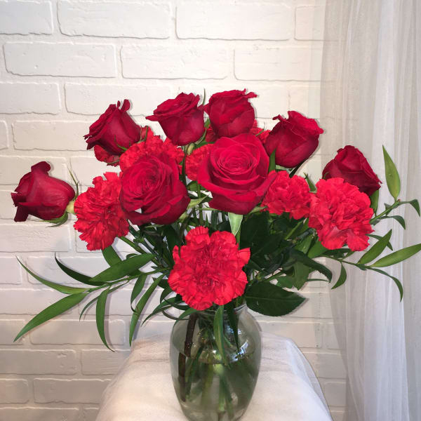 Red roses and carnations in a clear glass vase