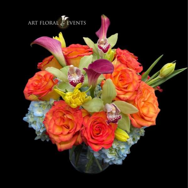 Orange roses with orchids and calla lilies in a glass vase