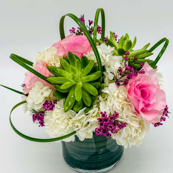 Pink and white flowers with a green succulent in a glass vase