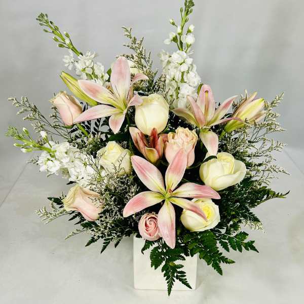 Pink lilies and cream roses in a white vase