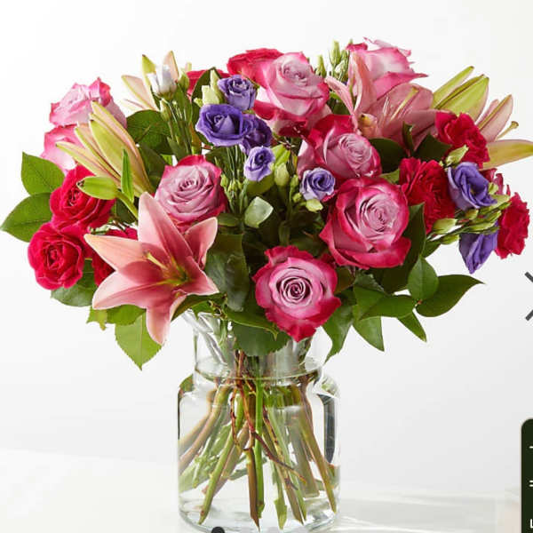 Bouquet of pink and purple roses with lilies in a glass vase