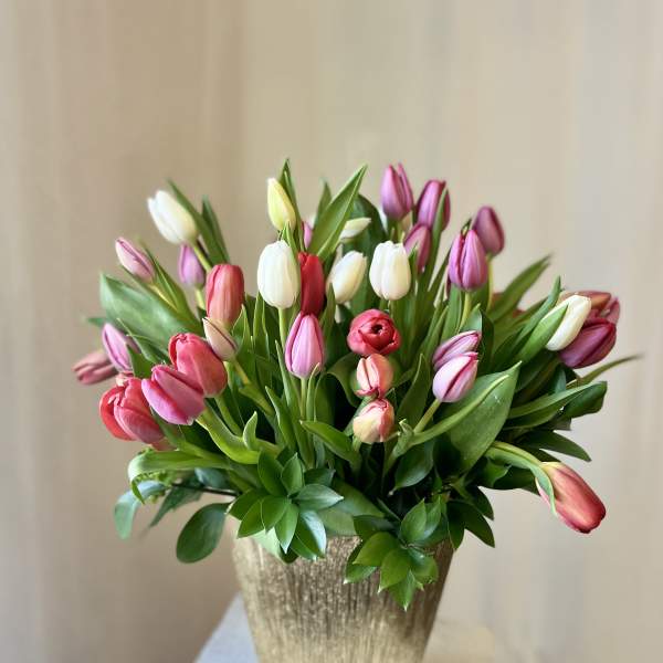 Bouquet of pink, white, and red tulips in a gold vase
