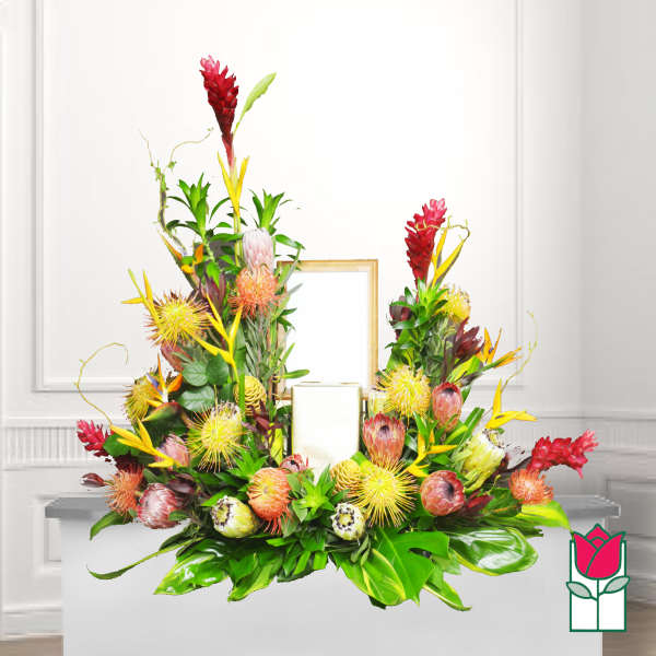 Tropical floral arrangement with red and yellow blooms around a candle