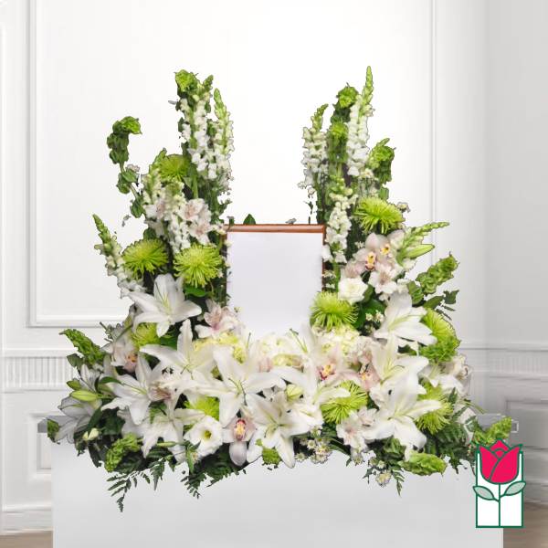 White floral funeral spray with lilies and green accents around a framed center