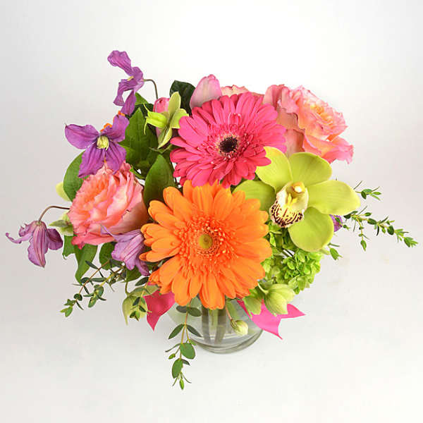 Bright mixed bouquet in a clear glass vase with pink, orange, and purple blooms