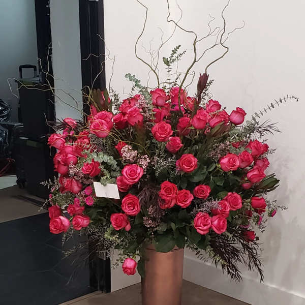 Large arrangement of pink roses in a tall copper vase