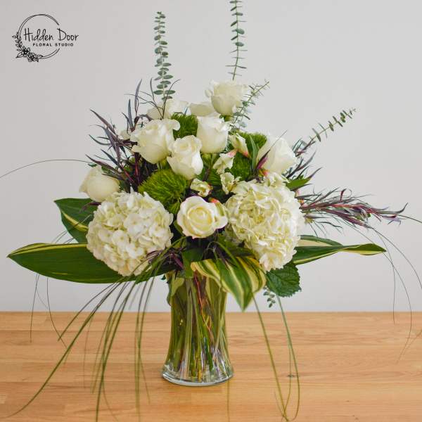 White roses and hydrangeas in a clear glass vase