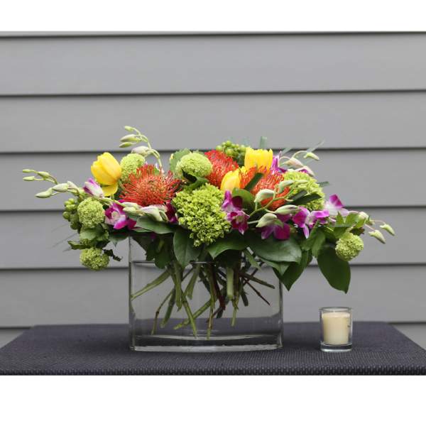 Mixed bouquet in a clear glass vase with a small candle beside it