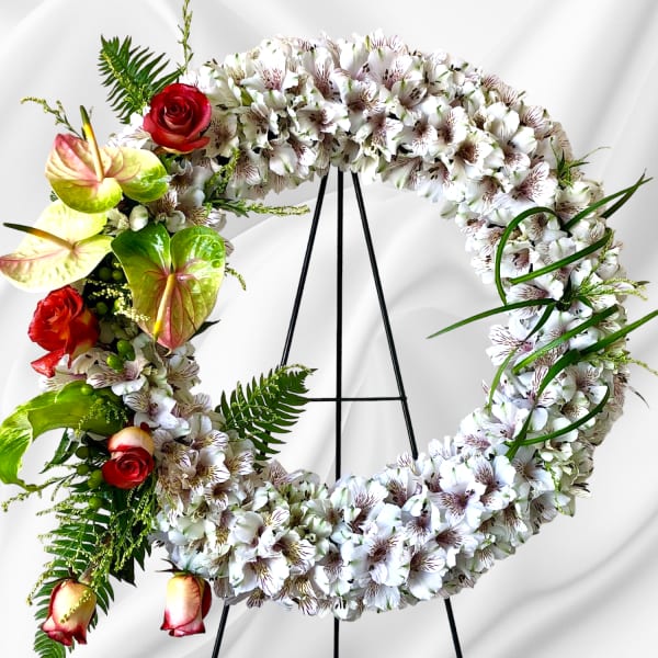 Circular floral wreath on an easel with white blooms and red roses