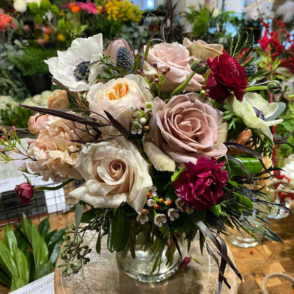 Mixed bouquet of roses, poppies, and carnations in a glass vase