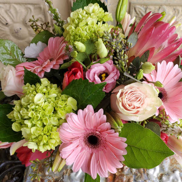 Pink gerbera daisies and roses with green hydrangeas in a bouquet