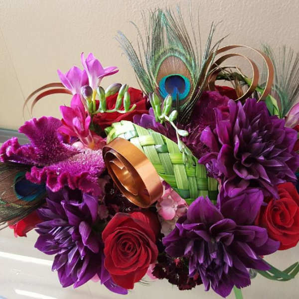 Bouquet of purple and red flowers with peacock feathers and ribbon loops