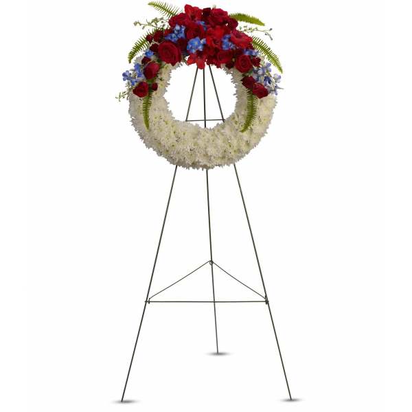 Standing floral wreath with red, white, and blue flowers on an easel