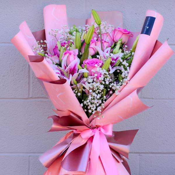 Pink bouquet of roses and lilies wrapped in pink paper