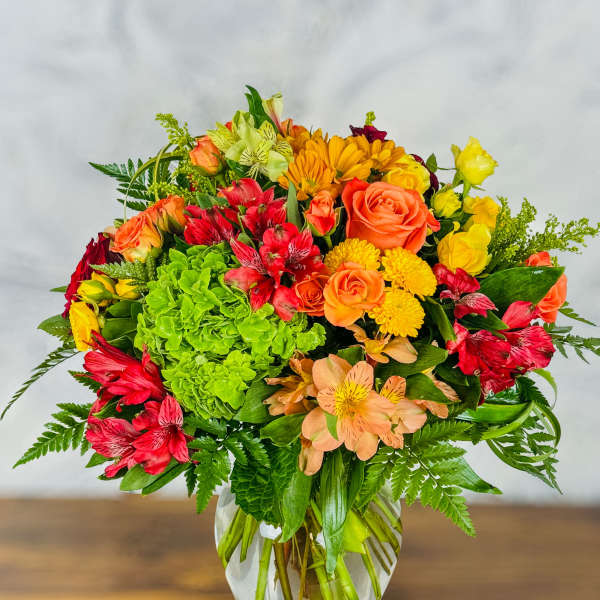 Mixed bouquet of roses, alstroemeria, and chrysanthemums in a glass vase