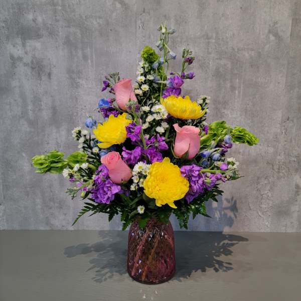 Colorful bouquet of yellow, pink, and purple flowers in a purple vase
