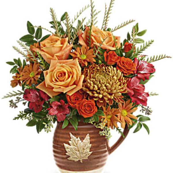 Autumn bouquet of orange and red flowers in a brown ceramic mug vase